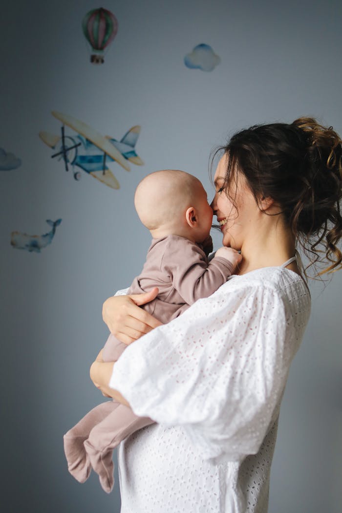 A tender moment of a mother holding her baby in a cozy, decorated nursery.